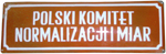 Białe napisy na czerwonym tle - tablica z napisem Polski Komitet Normalizacji i Miar - zdjęcie