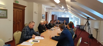  Drugie posiedzenie Rady Metrologii II kadencji w Kielcach.  uczestnicy siedzą przy stole w sali konferencyjnej słuchając wystąpienia prelegenta