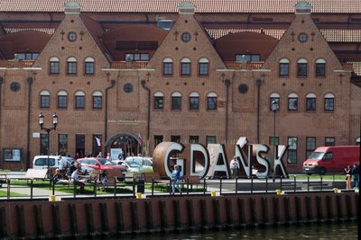  Zabytkowa zabudowa Starego Gdańska. Na zdjęciu budynek Filharmonii Bałtyckiej, położony nad rzeką. Przed budynkiem napis Gdańsk.