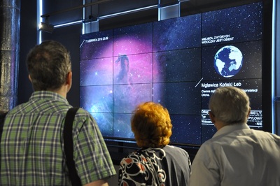  Trzy osoby wpatrują się w ekran, na którym wyświetlony jest fragment kosmosu.