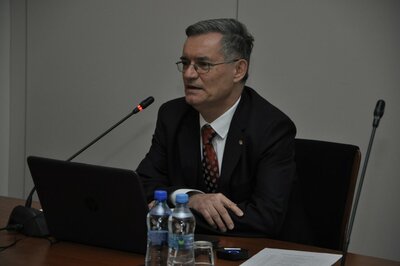  Na zdjęciu przed mikrofonem siedzi mężczyzna w garniturze: prowadzący seminarium doktor Paweł Fotowicz.