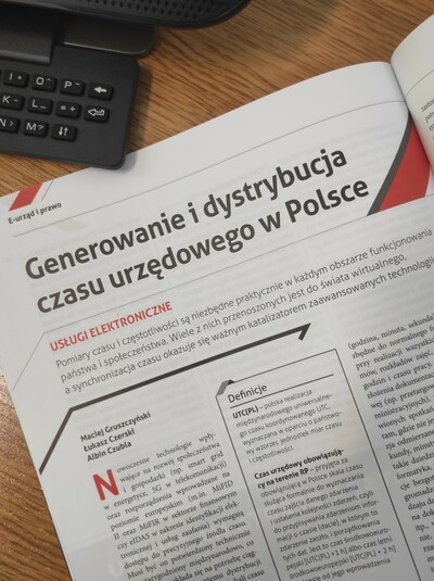 Na zdjęciu widok leżącej gazety z otwartą stroną z artykułem &quot;Generowanie i dystrybucja czasu urzędowego w Polsce&quot;.