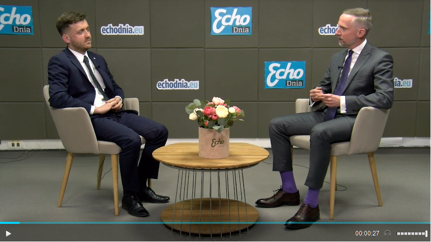 Kadr filmowy z rozmowy: na przeciwko siebie w fotelach siedzi dwóch mężczyzn w garniturach. Pośrodku mały okrągły stolik, a na nim kwiaty. Z tyłu, za mężczyznami ściana z logotypami "Echo Dnia".